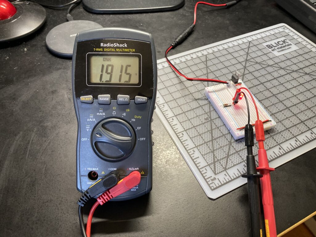 Probing the voltage drop across the red LED reads 1.915 volts.