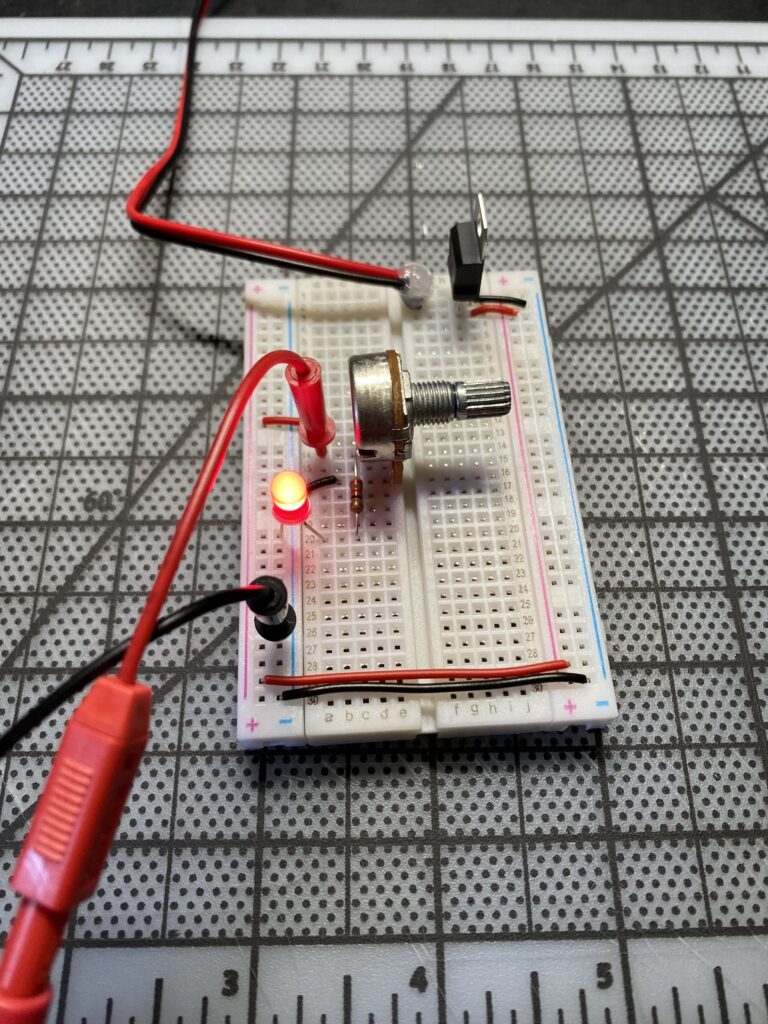 Circuit on a breadboard with red lit LED