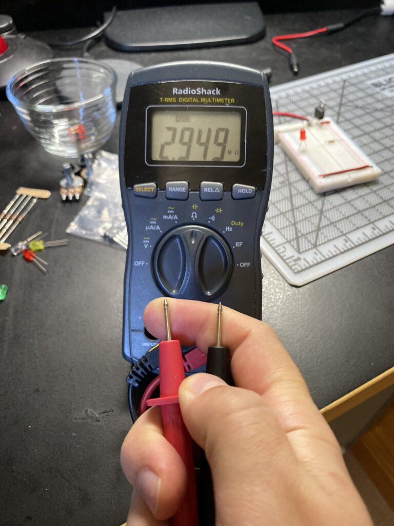A finger touching probes on multimeter